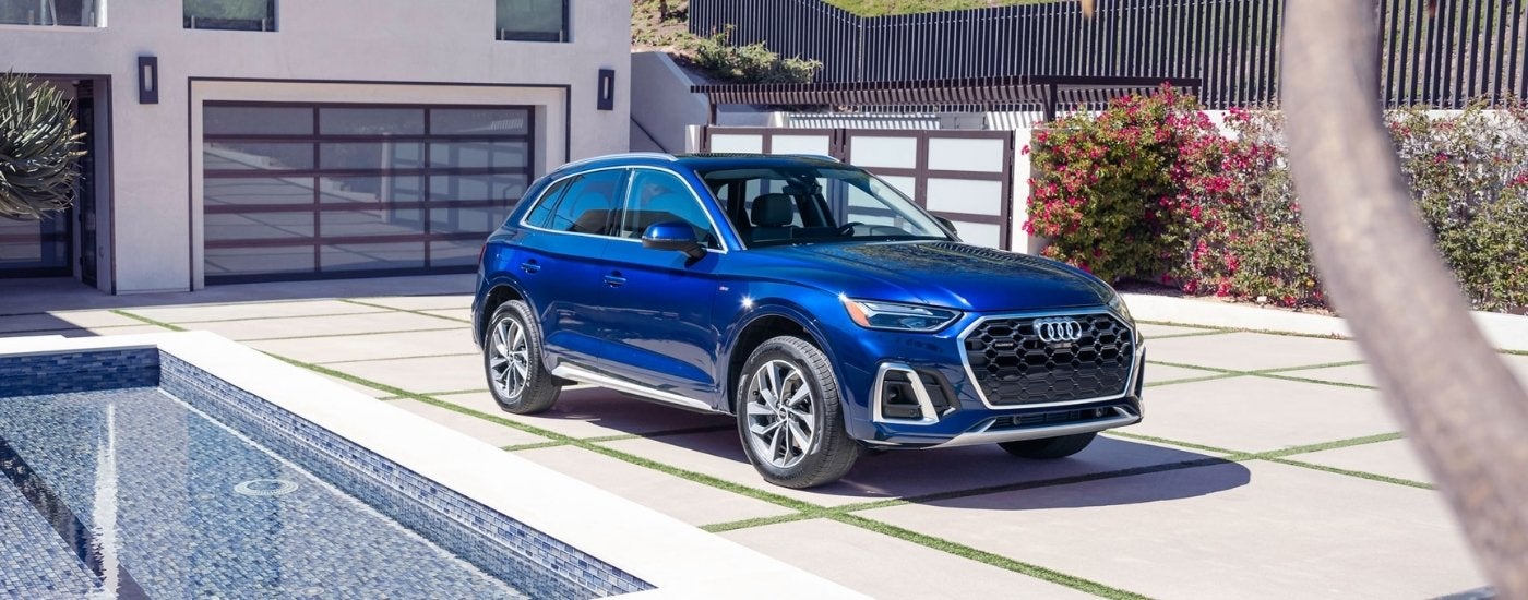 A blue 2025 Audi Q5 for sale parked next to a pool.